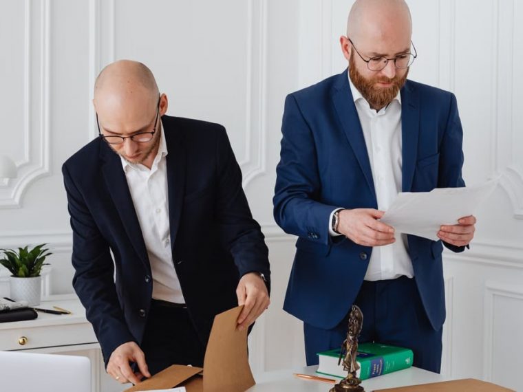 Two business professionals in corporate attire reviewing documents in a modern office setting.