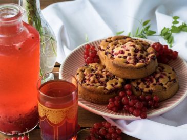 a plate of muffins next to a glass of tea