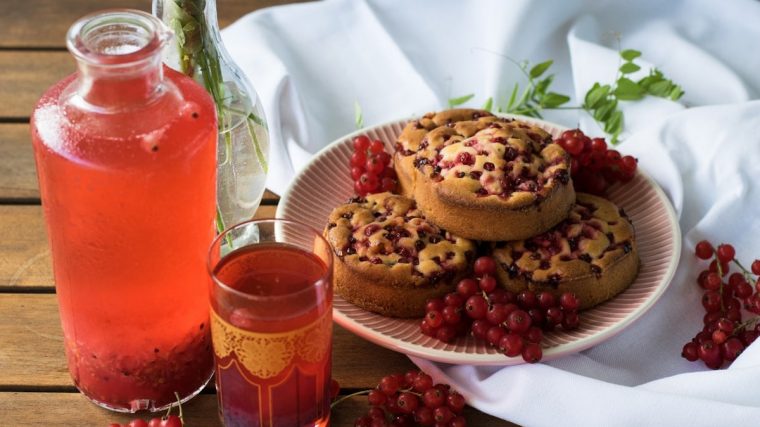 a plate of muffins next to a glass of tea